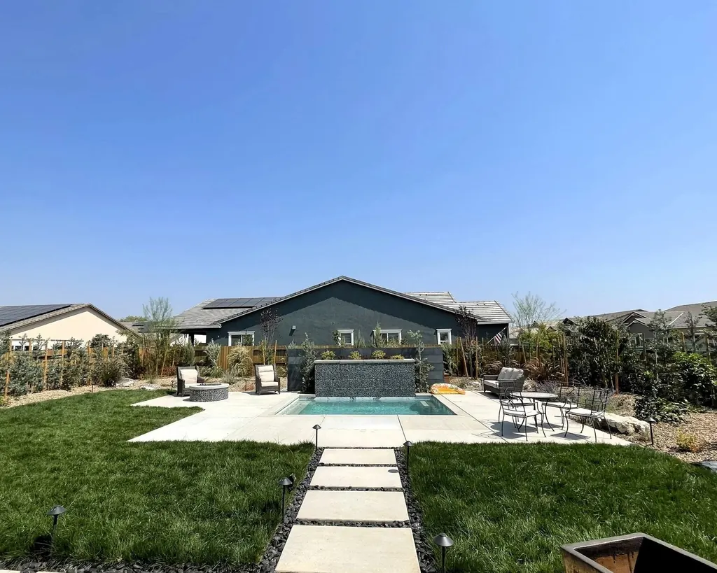 Concrete steppers crossing a lawn toward a pool and modern home