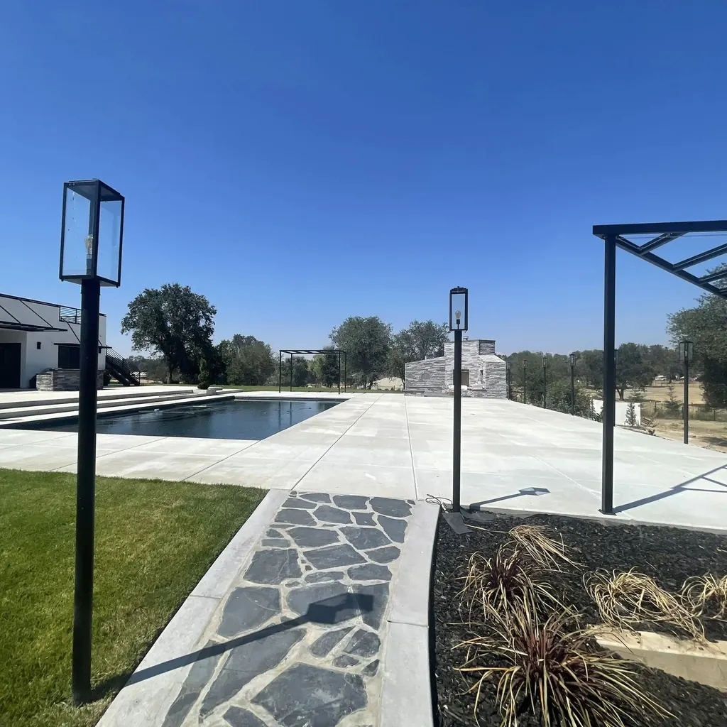 Flagstone path with post lanterns leading past lawn to the pool deck