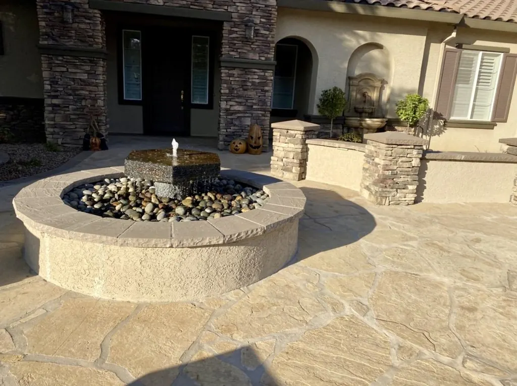 Round stone fountain filled with river rock in a front entry courtyard