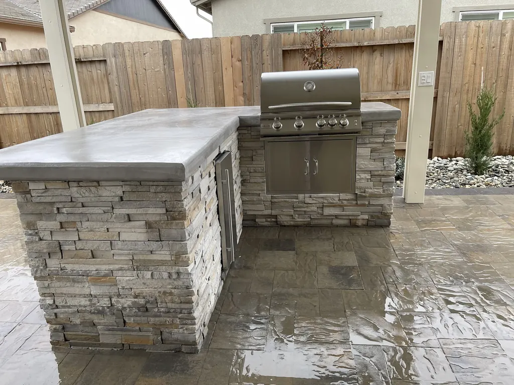 L-shaped stacked stone outdoor kitchen with a built-in grill