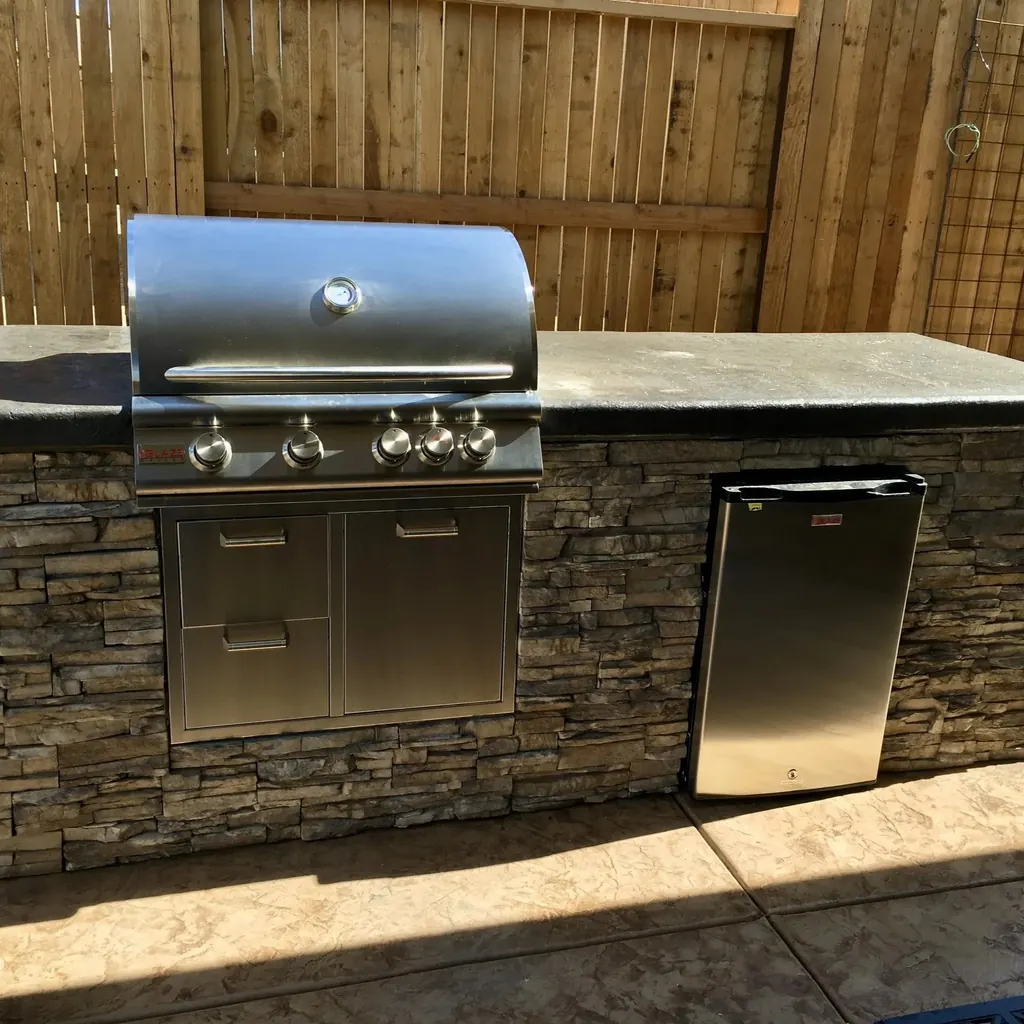 Built-in grill island finished in stacked stone with a stainless grill and storage