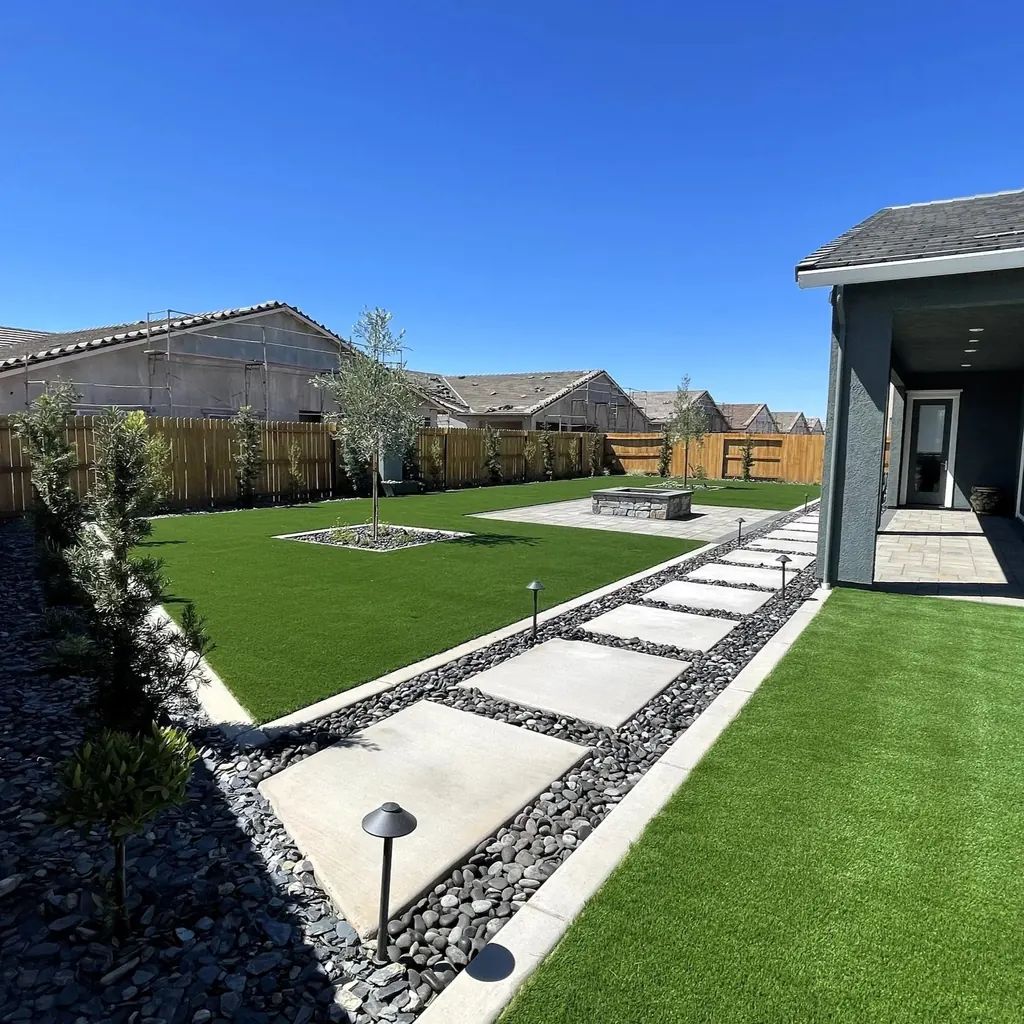Concrete steppers and low path lights crossing a lawn beside a modern home