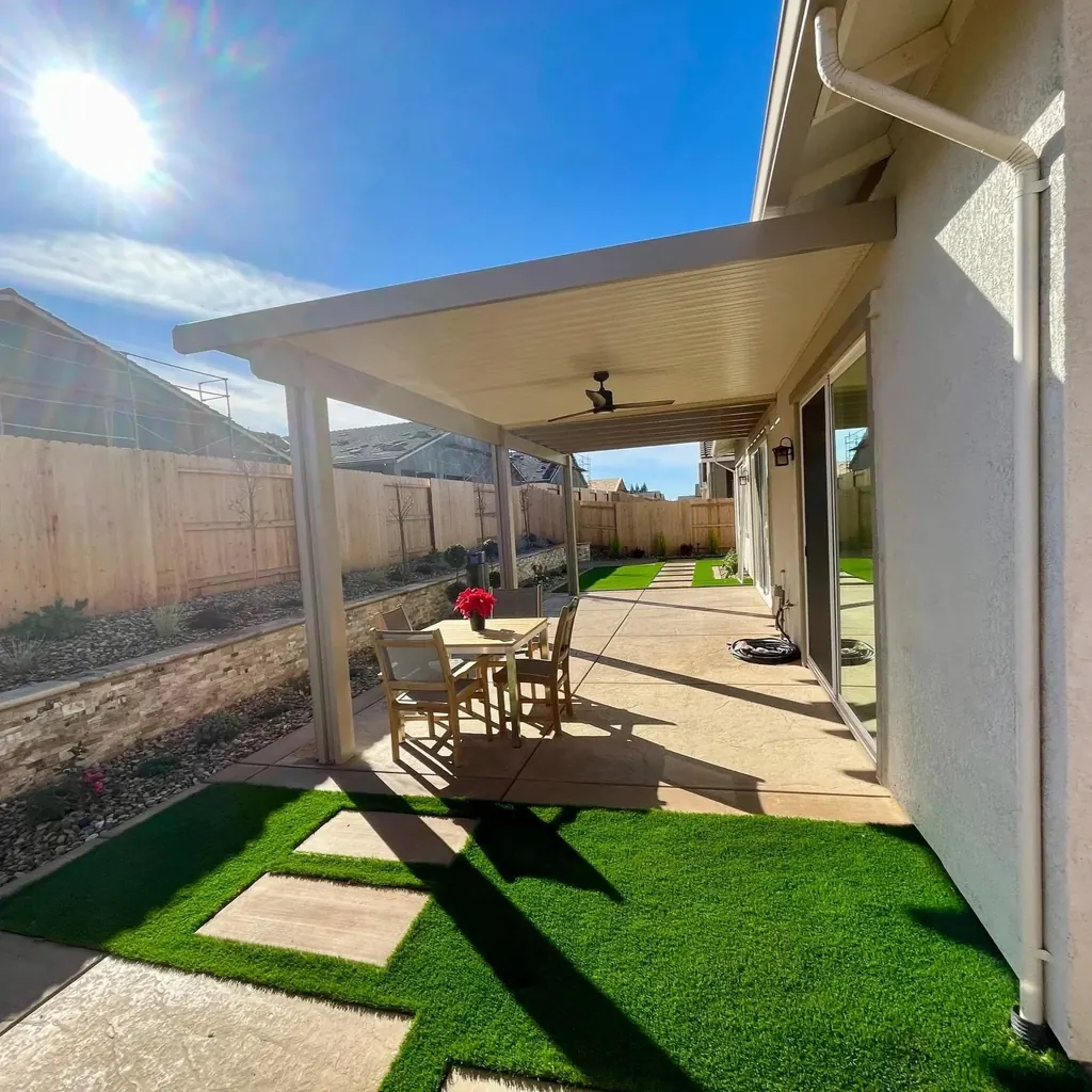 Patio cover with a ceiling fan over a dining table, with turf and steppers beyond
