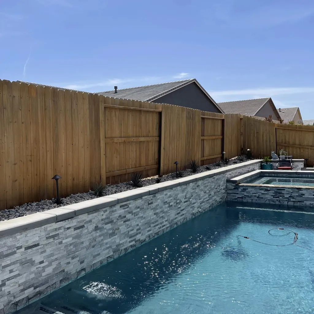 Long narrow pool with a stacked stone wall and a raised spa at the far end