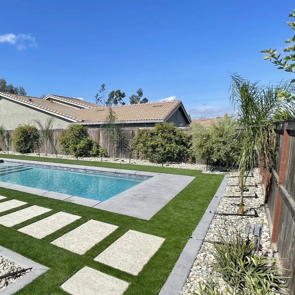 Small rectangular pool with concrete steppers set in turf beside a home