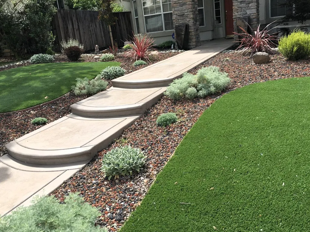 Wide curved concrete steps rising through turf and planting toward a house