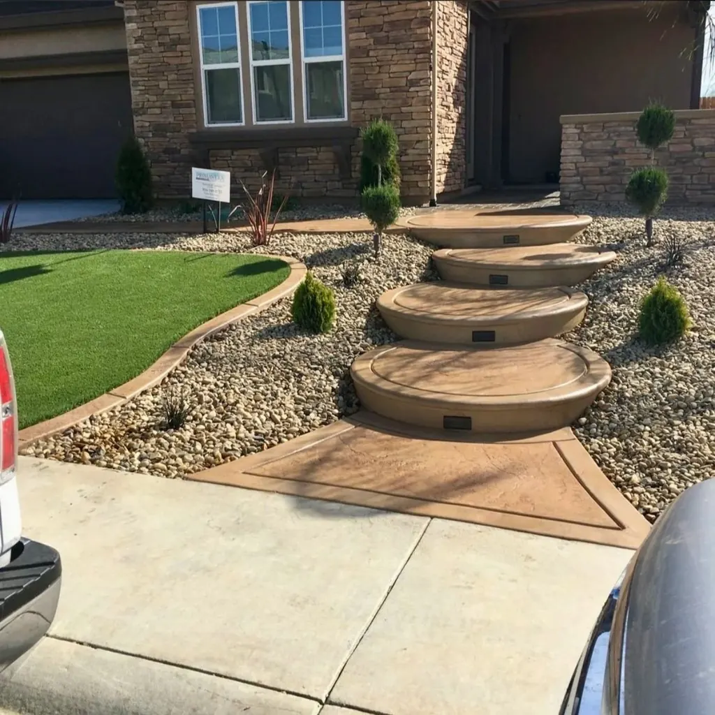 Curved concrete entry steps with river rock and topiary