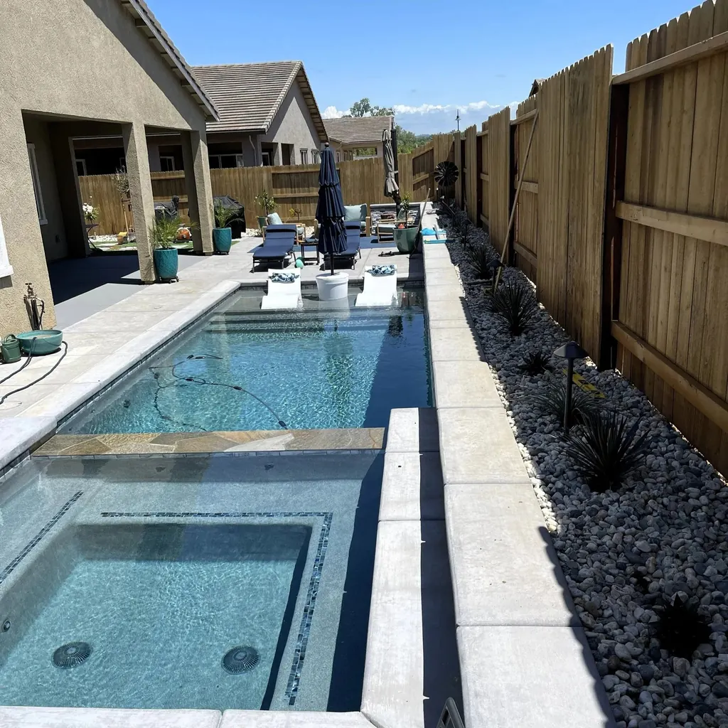 Raised spa overflowing into a long narrow pool beside the house