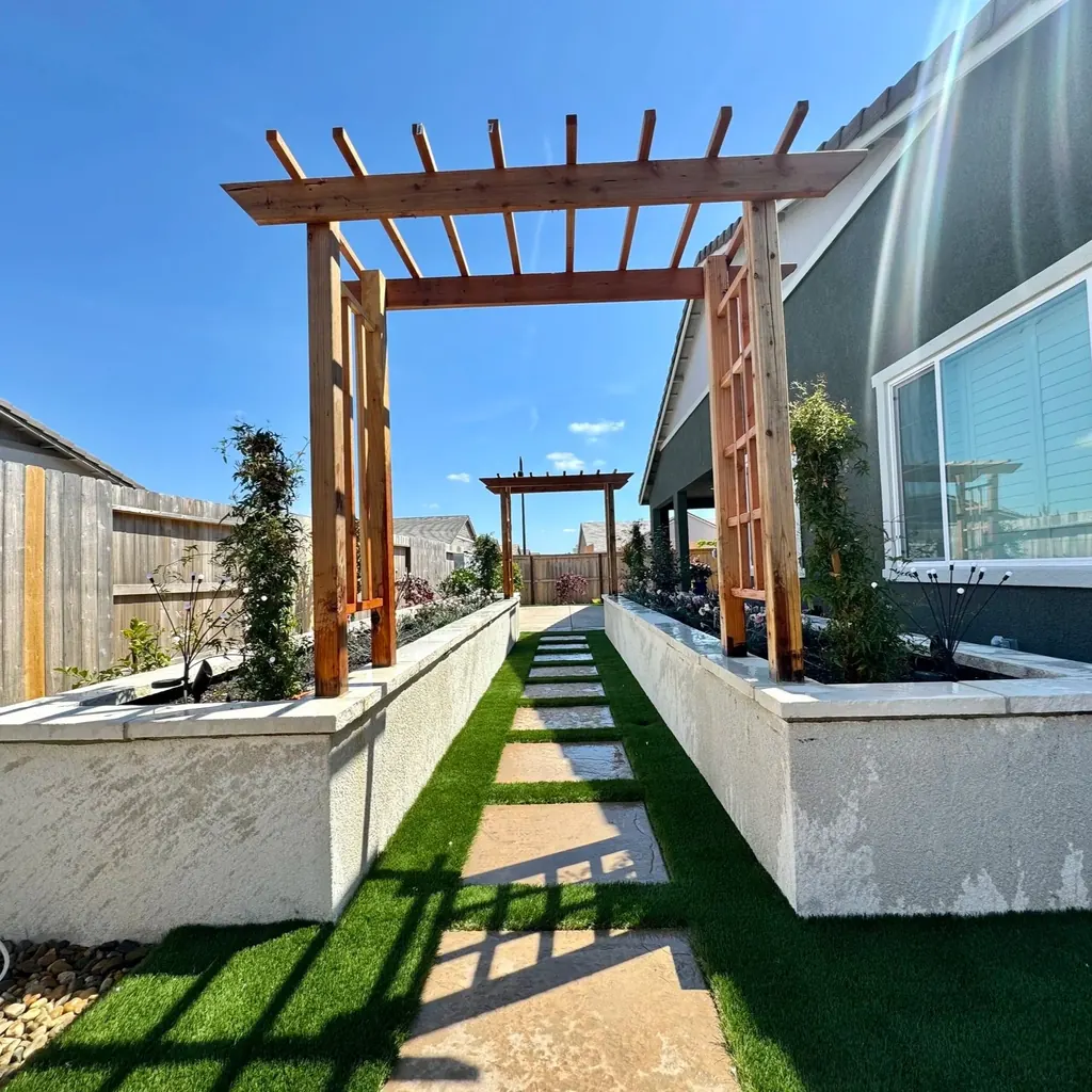 Wood pergolas framing raised planters and a narrow lawn path