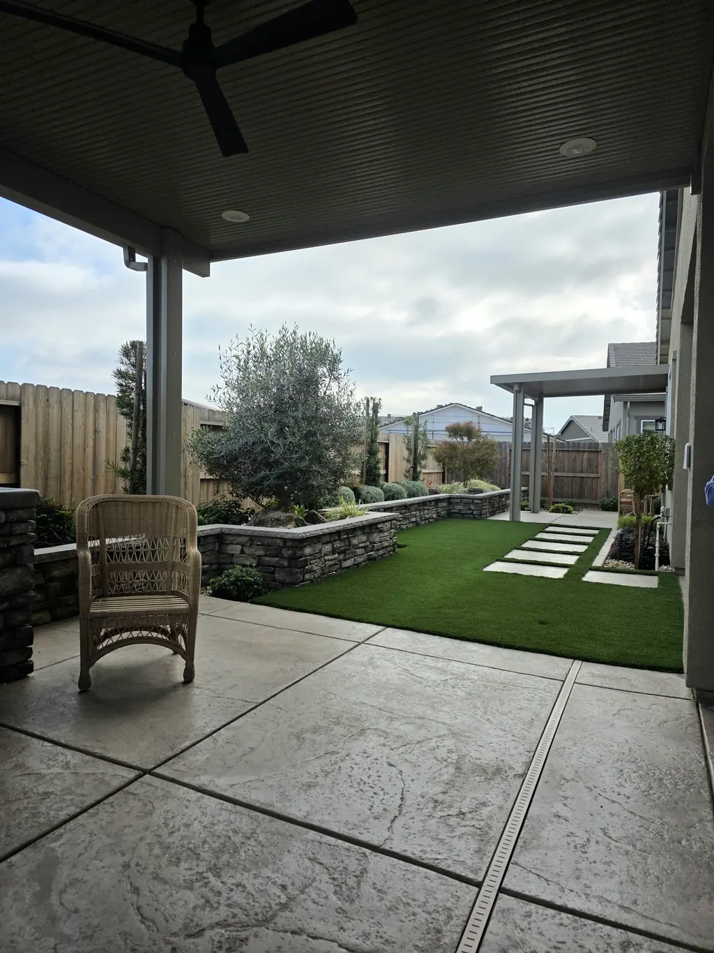 Covered patio opening onto lawn with steppers and low stacked stone walls