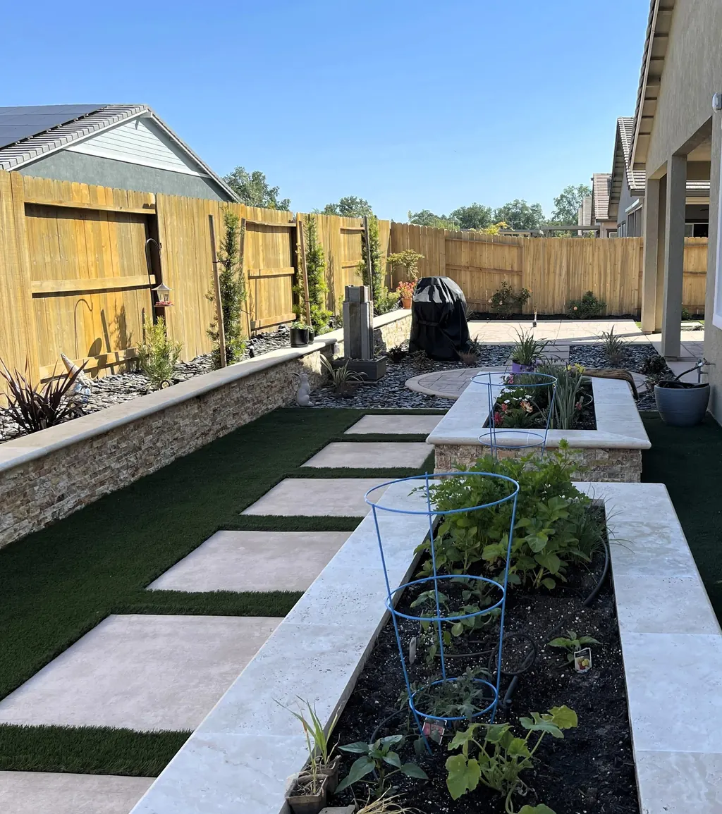 Raised stacked stone planters along a path of concrete steppers