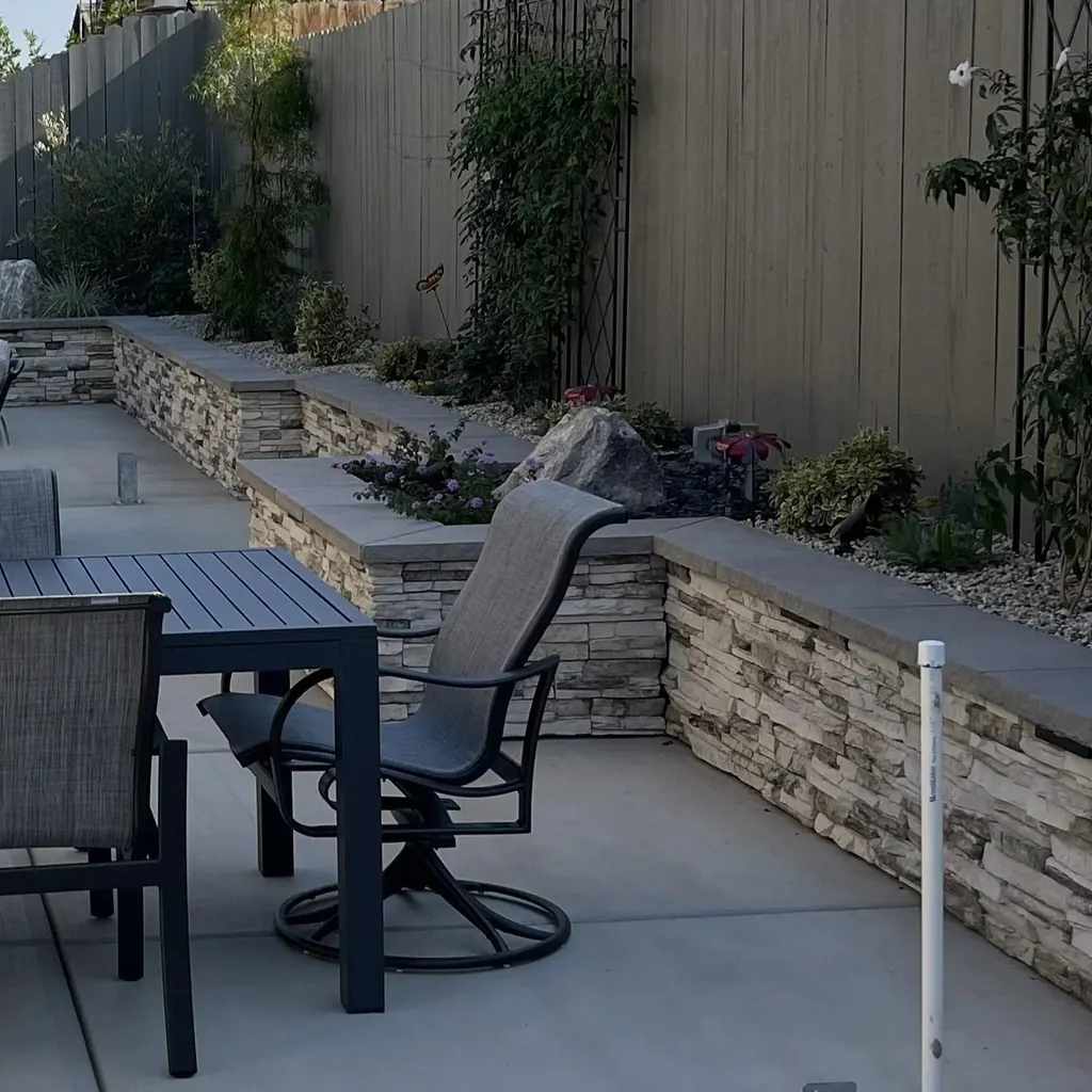 Stacked stone seat wall and planter beside a patio dining set